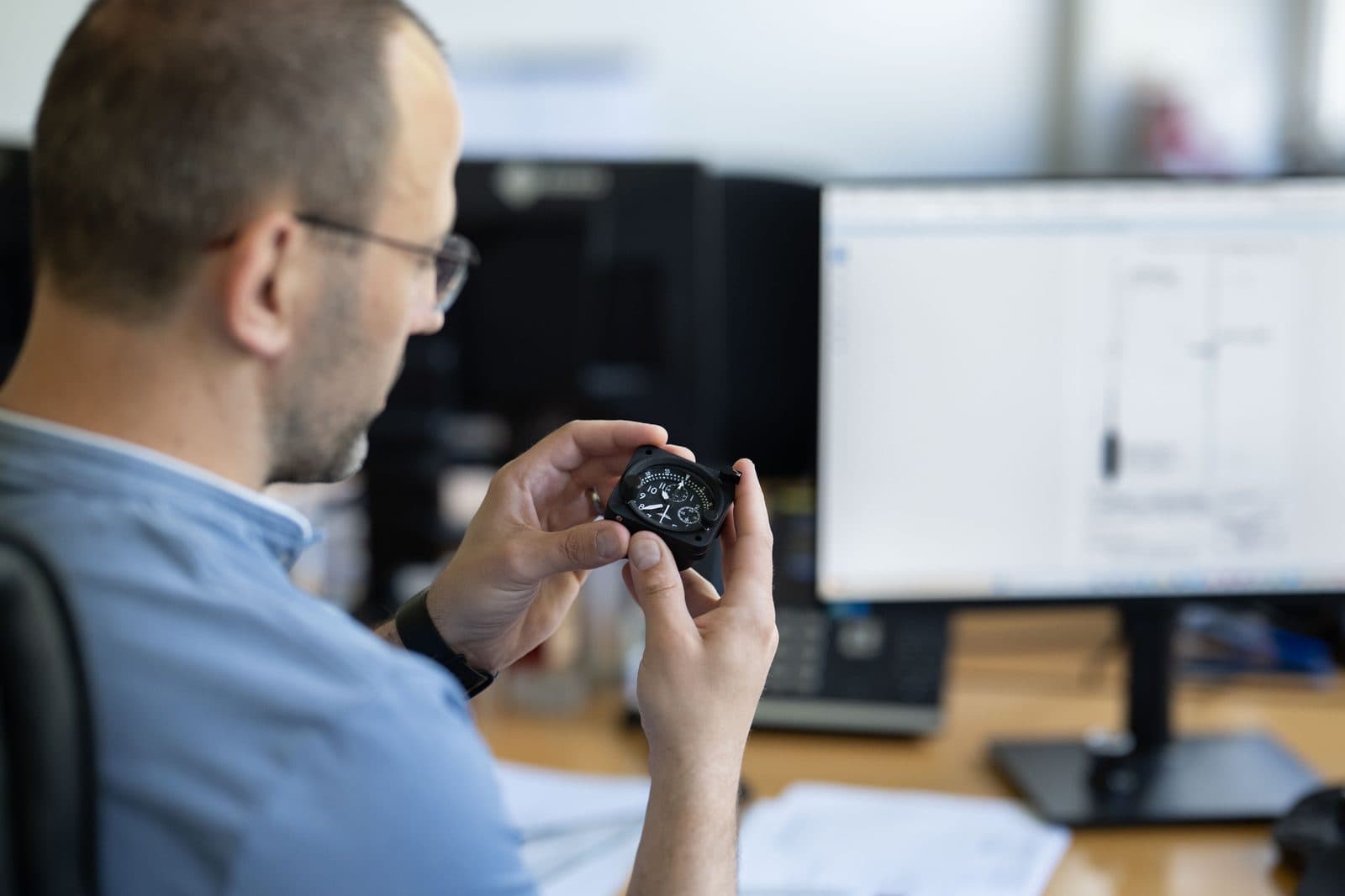 SATHOM engineer inspecting a flight instrument next to a technical drawing