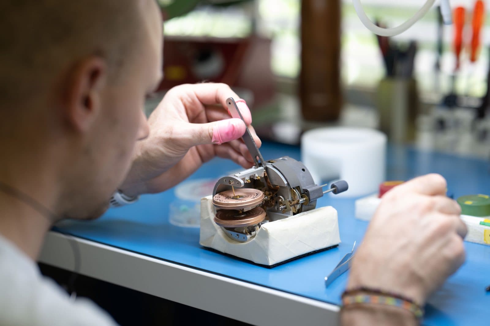 Technicien SATHOM assemblant un instrument mécanique de précision à l'établi